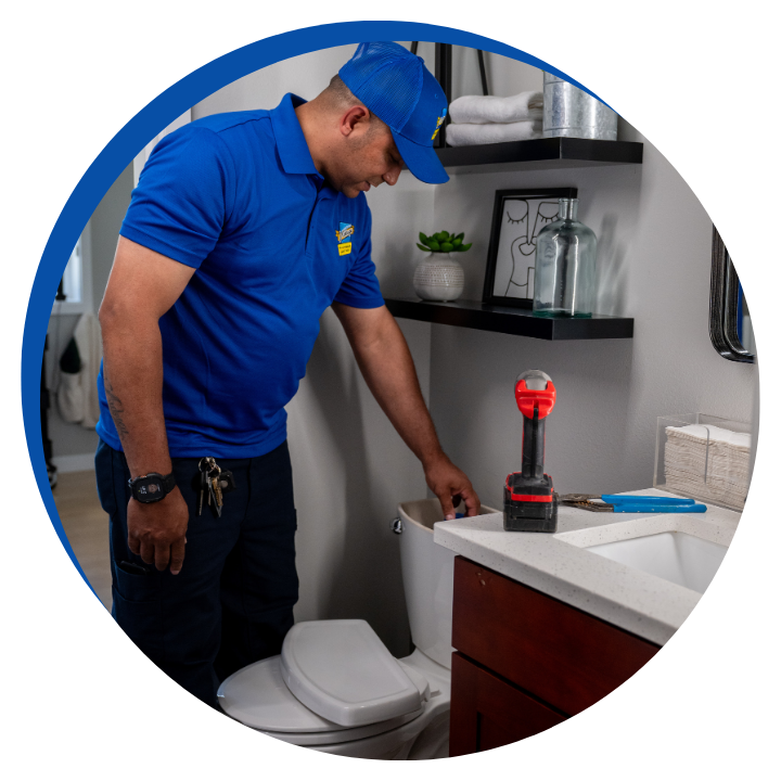 a worker examining a toilet for issues using tools in a bathroom